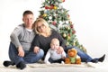 Mother, the father and their small child sits near Christmas tree Royalty Free Stock Photo