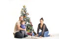 Mother, the father and their small child sits near Christmas tree Royalty Free Stock Photo