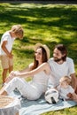 Mother, father, their son and little daughter, dressed in white clothes, take rest on the picnic in the park. Happy Royalty Free Stock Photo