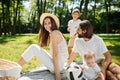 Mother, father, their son and little daughter, dressed in white clothes, take rest on the picnic in the park. Happy Royalty Free Stock Photo