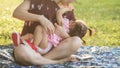 Mother feed breastmilk to her daughter in park Royalty Free Stock Photo