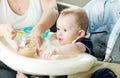 Mother feeding baby boy with fruit puree on kitchen Royalty Free Stock Photo