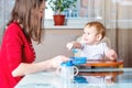 Mother feeding the baby holding hand with a spoon of food. Healthy baby nutrition. The emotions of a child while eating