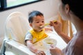 Mother Feeding Baby Sitting In High Chair, beginning solid food for little baby. little girl eating vegetables and Healthy nutriti Royalty Free Stock Photo