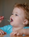 Mother feeding baby with spoon. Giving fruit sauce to little boy. Royalty Free Stock Photo