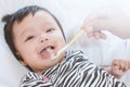 Mother feeding cute asian baby girl with a spoon at home Royalty Free Stock Photo