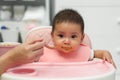 mother feeding food to her infant baby eating with spoon at home Royalty Free Stock Photo