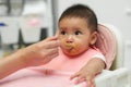 mother feeding food to her infant baby eating with spoon at home Royalty Free Stock Photo