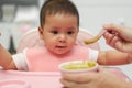 mother feeding food to her infant baby with spoon at home Royalty Free Stock Photo