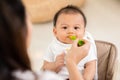 Mother feeding her asian baby daughter with pumpkin mashed or vegetable mash for vitamin on rubber spoon.Mom trying feed little Royalty Free Stock Photo