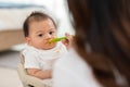 Mother feeding her asian baby daughter with pumpkin mashed or vegetable mash for vitamin on rubber spoon.Mom trying feed little Royalty Free Stock Photo