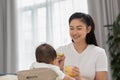 Mother feeding her asian baby daughter with pumpkin mashed or vegetable mash for vitamin on rubber spoon.Mom trying feed little Royalty Free Stock Photo