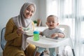 Mother feeding her baby boy while sitting on high chair Royalty Free Stock Photo