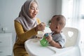 Mother feeding her baby boy while sitting on high chair Royalty Free Stock Photo