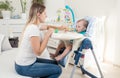 Mother feeding her baby in highchair at living room Royalty Free Stock Photo