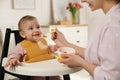 Mother feeding her little baby at home. Kid wearing silicone bib Royalty Free Stock Photo