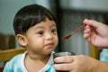 Mother feeding her baby with spoon. Mother giving healthy food to her adorable child at home. Royalty Free Stock Photo