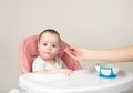 Mother feeding her cute baby girl in chair on grey background Royalty Free Stock Photo