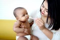 Mother feeding her cute little girl Asian African American baby daughter with spoon of food, infant kid enjoy eating healthy Royalty Free Stock Photo