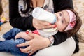 Mother feeding her little baby girl from the milkbottle