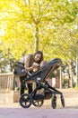 Mother feeding her son with a milk bottle in the park inside the baby stroller