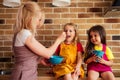 Mother feeding two daughters in the kitchen sitting on the table Royalty Free Stock Photo