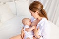 Mother feeds baby 6 months of breast sitting on a white bed at home, place for text Royalty Free Stock Photo