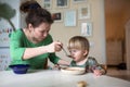 Mother feeds the child soup in the bright kitchen at home