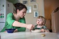 Mother feeds the child soup in the bright kitchen at home