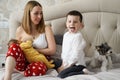 the mother feeds the newborn baby breast milk on the bed with elder brother