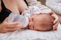 A mother feeds a newborn baby with a mixture from a bottle. A woman with a baby boy on a pillow for feeding children Royalty Free Stock Photo