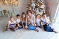 Mother and five children playing sparkler near Christmas tree at home