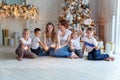 Mother and five children playing sparkler near Christmas tree at home