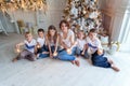 Mother and five children playing sparkler near Christmas tree at home