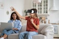 Mother freelancer working remotely on laptop from home while her child daughter using vr glasses Royalty Free Stock Photo