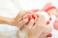Mother gentle hands with red nails holding newborn baby legs. Royalty Free Stock Photo