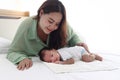 Mother gentle touching newborn infant baby boy on bed in white bedroom, lovely family mom and child stand time together, parent