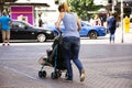 Mother german people push stroller carriage with baby and talking mobile phone on footpath in Heidelberg, Germany