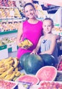 Mother with girl picking bananas on market Royalty Free Stock Photo
