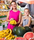 mother with girl picking bananas on market . Royalty Free Stock Photo
