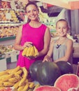 Mother with girl picking bananas on market Royalty Free Stock Photo