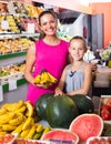 Mother with girl picking bananas on market Royalty Free Stock Photo