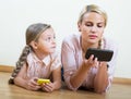 Mother and girl playing with mobile phones indoor Royalty Free Stock Photo