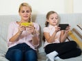 Mother and girl playing with mobile phones indoor Royalty Free Stock Photo