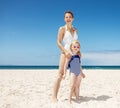 Mother and girl in swimsuits at sandy beach on a sunny day Royalty Free Stock Photo