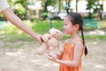 Mother give a teddy bear doll for her daughter in the park outdoor. Gift from mom for girls. Close-up happy kid with smiling Royalty Free Stock Photo