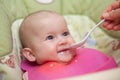 Mother gives baby food from a baby spoon. Smiling baby eating food first time. weaning baby Royalty Free Stock Photo