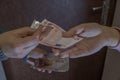 Mother gives money to her daughter standing on the right for shopping in the store against the background of brown front door Royalty Free Stock Photo