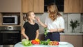 Mother gives teen daughter to taste parsley in kitchen Royalty Free Stock Photo