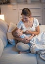 Young mother giving bottle of milk to her hungry baby at night Royalty Free Stock Photo